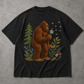 SF_COLOR=black; SF_ITEM=adult-t-shirt; SF_ROLE=main; Funny Bigfoot Blowing A Dandelion T-Shirt Retro Floral Sasquatch Outdoors Tee - Black Adult T-Shirt product image